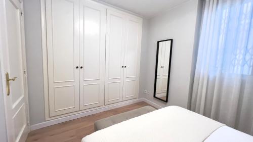 a white bedroom with white cabinets and a mirror at Cervantes Prime in Valencia