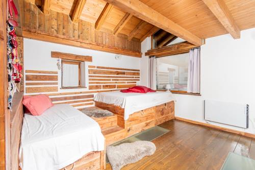 two beds in a room with wooden walls at Chalet Palù in Brosso