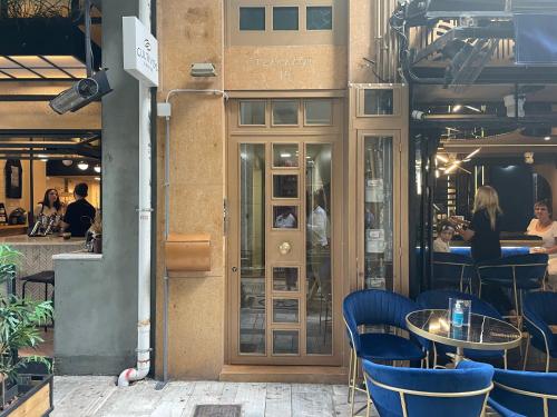 Tsakalof 10 View Central Apartment by SuperHost Hub في أثينا: مطعم والكراسي الزرقاء والناس جالسين على الطاولات