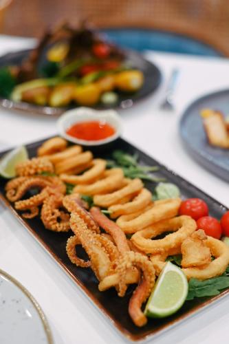 a plate of food with onion rings and tomatoes at Royal G Max in Golem