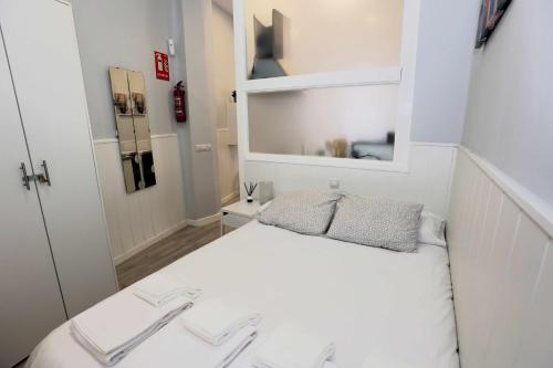 Dormitorio pequeño con cama blanca y espejo en La casita de Valvanera, en Madrid