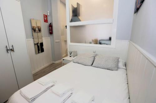 a small bedroom with a white bed and a mirror at La casita de Valvanera in Madrid