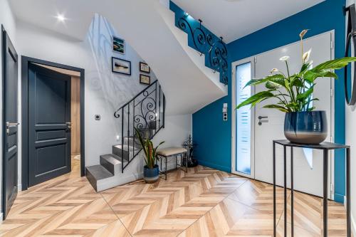 a hallway with blue walls and stairs with a potted plant at SUITE ET CHAMBRES COSY CHEZ A&M -ELEGANT HOME, CALME, CAMPAGNE, PARKING gratuit in Épône