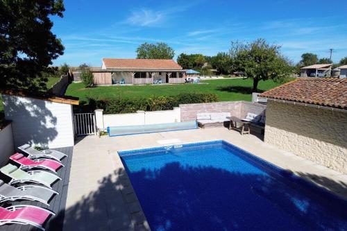 a swimming pool in a yard with chairs and a house at La Bourdetaise in Le Bourdet