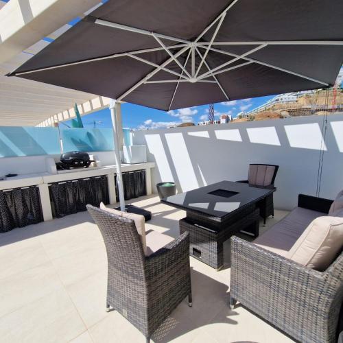 a patio with a table and chairs and an umbrella at Dúplex con vistas impresionantes in Fuengirola