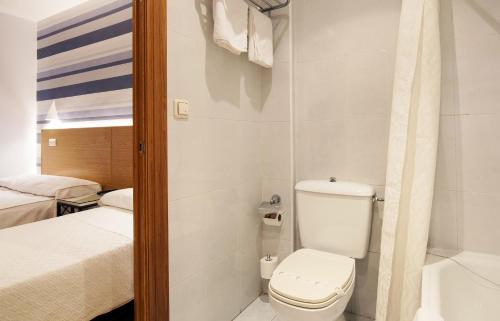 y baño pequeño con aseo y bañera. en Hostal Bezana, en Burgos