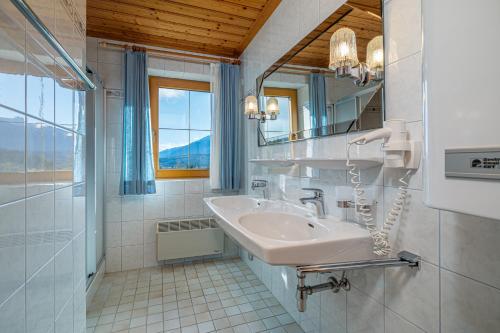 W białej łazience znajduje się umywalka i lustro. w obiekcie Appartements Spitzegel w mieście Hermagor