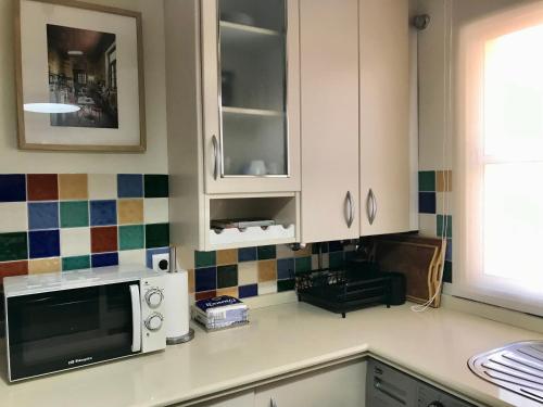 eine Küche mit weißen Schränken und einer Mikrowelle in der Unterkunft Ático con vistas cerca del mar - Penthouse - parking - terraza in Torre del Mar