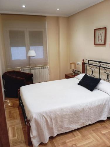 a bedroom with a large white bed and a chair at El rinconín de Luanco in Luanco