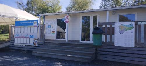 a small white house with a front porch with a green trash can at LJ Cosy Lodge - Mobilhome in Houlgate
