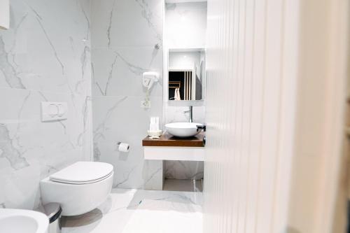 a white bathroom with a toilet and a sink at Royal G Max in Golem