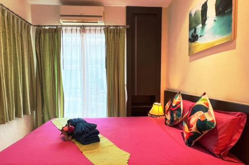 a bedroom with a pink bed with pillows on it at Quiet Patong Apartment near Night Life & Good Food in Patong Beach