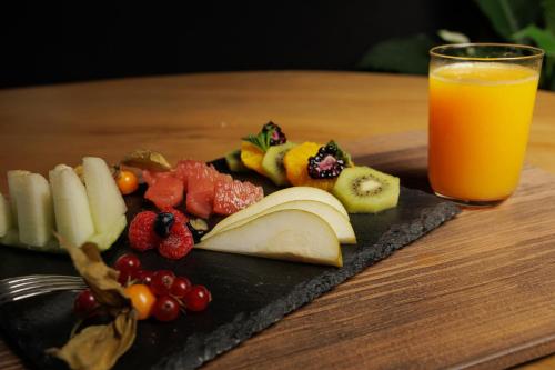 a plate of fruit and a glass of orange juice at Hotel & Spa El Mirador de Ulzama in Urrizola-Galáin