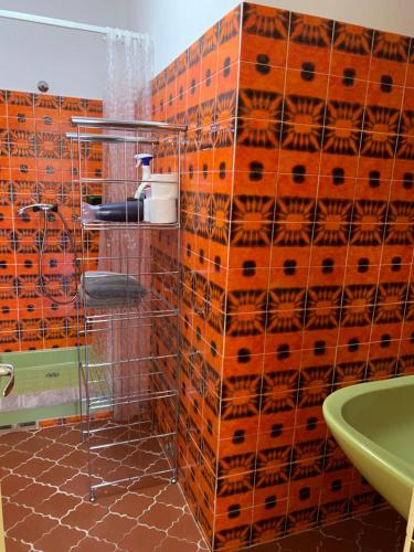 La salle de bains est pourvue d'un mur en carrelage orange et d'un lavabo. dans l'établissement Les Oliviers, à Grimaud