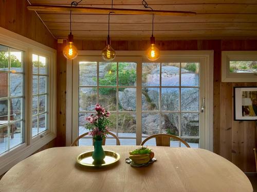 a dining room with a table with a vase of flowers at Idyllic Cabin in Lillesand fantastic ocean view in Lillesand