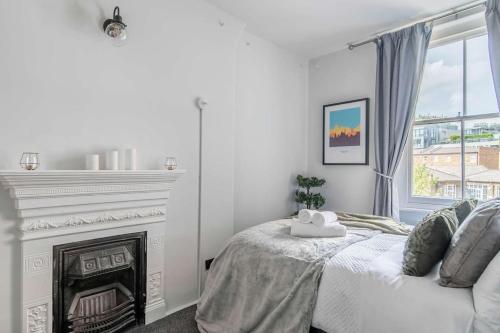 a white bedroom with a bed and a fireplace at Lovely apartment - Great Portland Street - LONDON ZOO - CENTRAL LOCATED in London