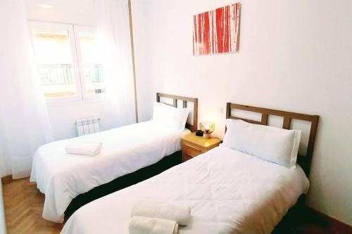 two beds in a small room with white sheets at Manzanares Getaway in Manzanares el Real