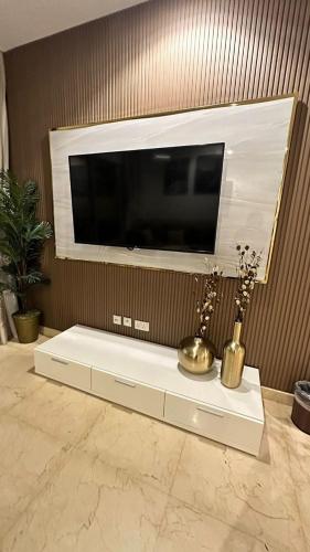 a flat screen tv on a wall above a white table at داماك الكورنيش جدة الجناح الذهبي Damac tower jeddah in Jeddah