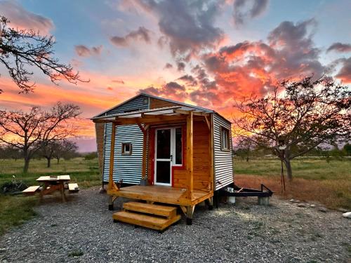 a small wooden cabin with a picnic table and a sunset at Namakai.tinyhouse, minimalism in a magic place in Los Árboles