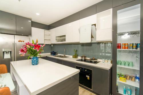 a kitchen with white cabinets and a vase of flowers on a counter at Căn hộ cao cấp 3 phòng ngủ view cầu hàn, cầu rồng, biển in Da Nang