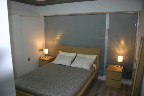 APARTAMENTO EXCLUSIVO EN EL CASCO HISTORICO في ألميريا: غرفة نوم بها سرير ومصباحين على الطاولات