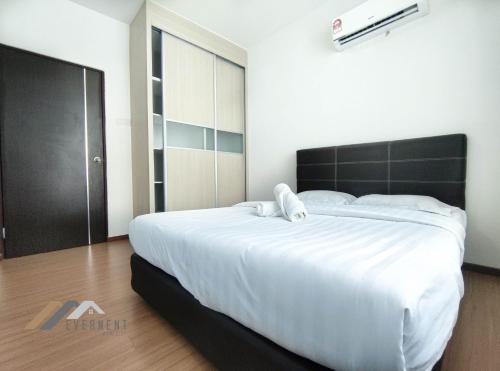 a bedroom with a large white bed with a black headboard at Serene Heights by Evernent in Miri