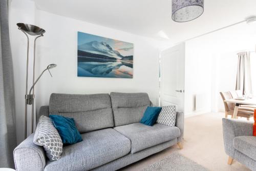 uma sala de estar com um sofá cinzento e almofadas azuis em Homely 4BD Townhouse - Next to Hanley Park em Stoke-on-Trent