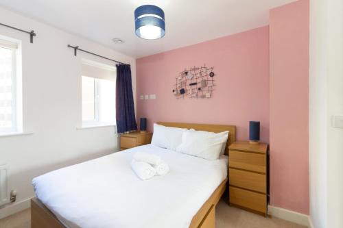 a bedroom with a bed with white sheets and pink walls at Homely 4BD Townhouse - Next to Hanley Park in Stoke on Trent