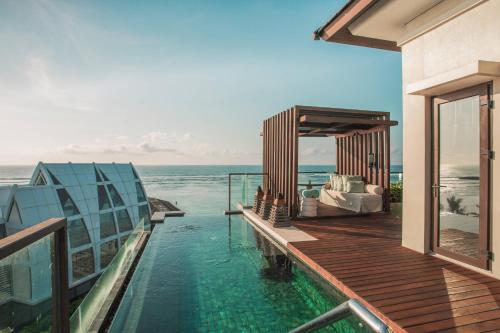 a house with a swimming pool next to the ocean at The Ritz-Carlton Bali in Nusa Dua