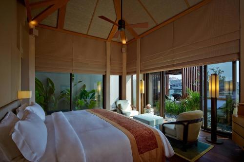 a bedroom with a large bed in a room with large windows at The Ritz-Carlton Bali in Nusa Dua