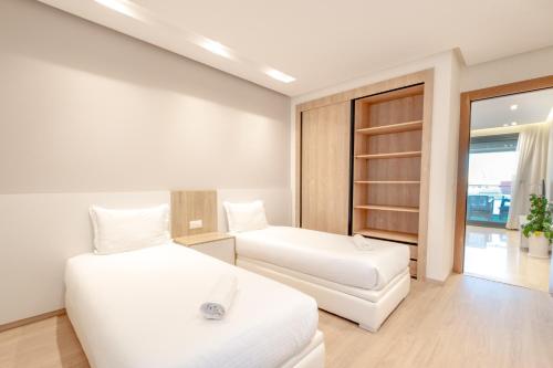 um quarto branco com 2 camas e um banco em Luxury Apartments em Tânger