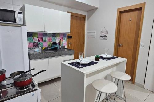 a kitchen with white cabinets and bar stools and a stove at Apt Lindo e Completo no centro in Belém