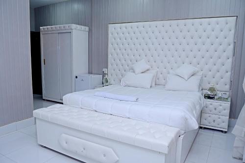 a white bedroom with a large white bed with a large headboard at Pakistan Club Inn Hotel in Kalar Goth