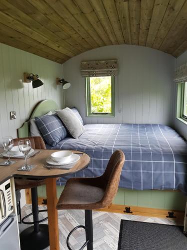 a bed and a table in a room with a bed at Braeside Shepherd's Hut - Greenhead - Hadrian's Wall - Northumberland in Greenhead