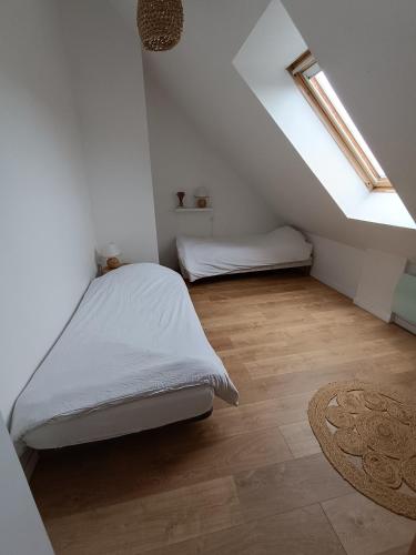 a white bedroom with a bed and a rug at Gîte chez Julie et Franck in Cappy