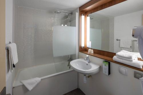 een badkamer met een wastafel, een douche en een spiegel bij Noemys ARLES in Arles
