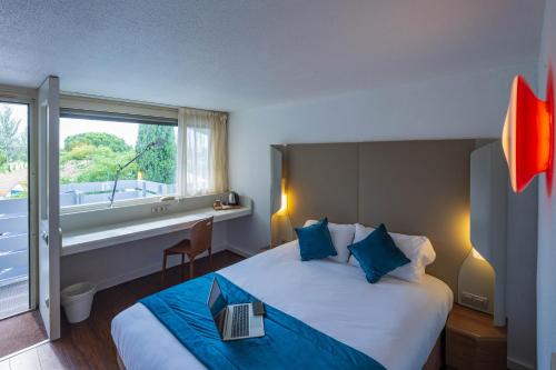 een hotelkamer met een bed met een laptop erop bij Noemys ARLES in Arles