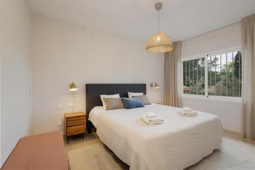 a bedroom with a large white bed and a window at Luxurious frontline golf apartment in Elviria in Marbella