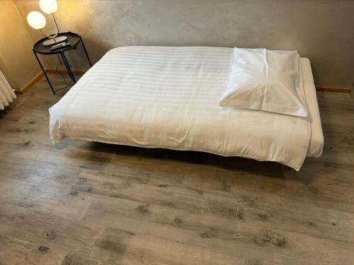 a bed with white sheets and pillows on a wooden floor at Basiglio Centro Storico in Basiglio