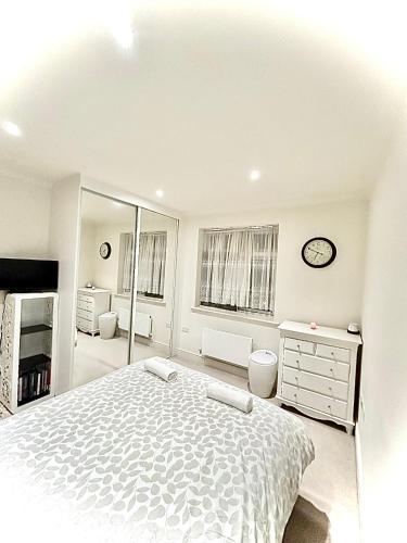 a white bedroom with a bed and a mirror at Lovely cosy apartment Bromley in Bickley