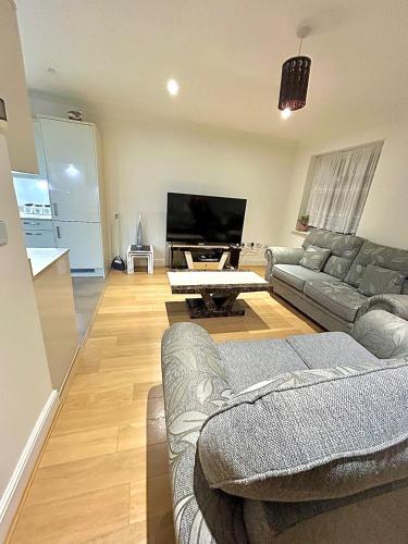 uma sala de estar com 2 sofás e uma televisão de ecrã plano em Lovely cosy apartment Bromley em Bickley