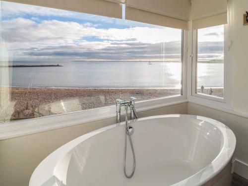 a bath tub in a bathroom with a large window at Fairwinds in Newbiggin-by-the-Sea