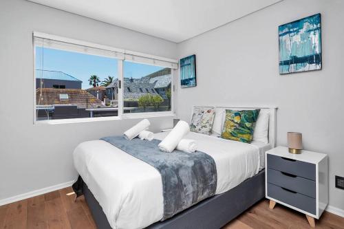 a white bedroom with a bed and a window at Two Bedroom House with Views of Lions Head in Cape Town