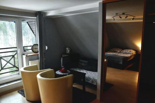 a room with two chairs and a bedroom with a bed at Leśny Dwór in Wisła