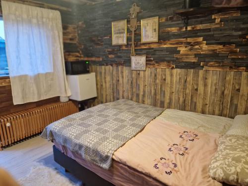 Hunters little house في Gardur: غرفة نوم بسرير وجدار خشبي