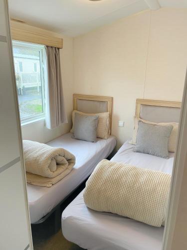 2 łóżka w małym pokoju z oknem w obiekcie 3 bedroom luxury caravan haven, marton mere w Blackpool
