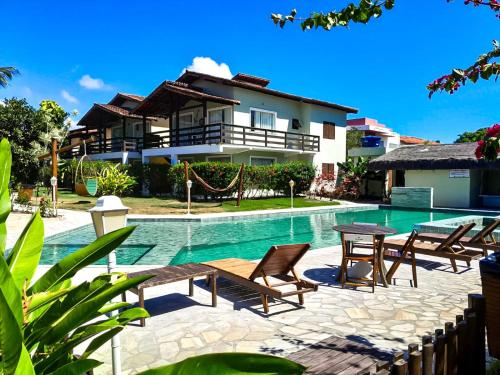 a villa with a swimming pool in front of a house at Village Muta in Porto Seguro