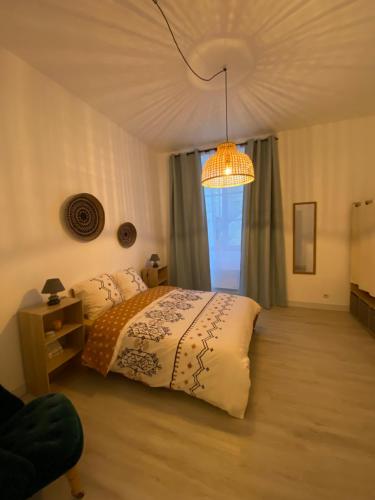 a bedroom with a bed and a chandelier at Appartement Cosy avec vue sur le château in Chinon