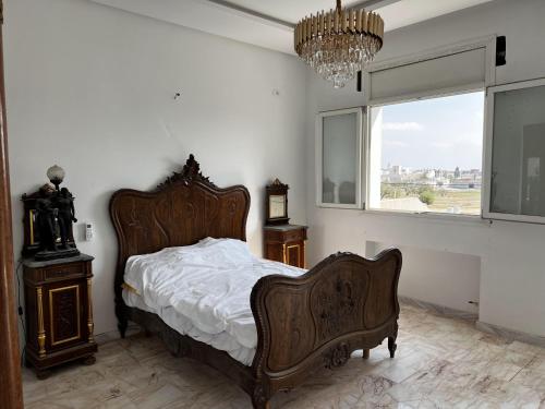 Schlafzimmer mit einem Bett, einem Fenster und einem Kronleuchter in der Unterkunft Villa Olympus - Monastir 