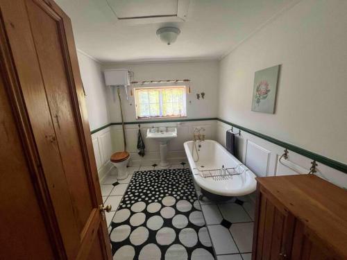 La salle de bains est pourvue d'un lavabo, de toilettes et d'une baignoire. dans l'établissement The Cottage on West, à Greyton
